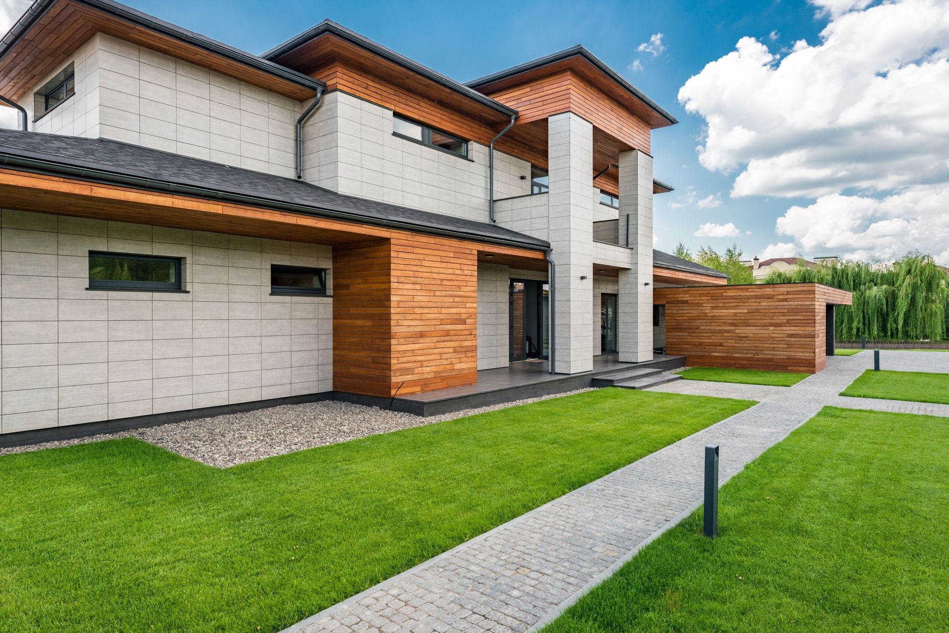 Exterior of contemporary residential house with green lawn and paths in sunny day